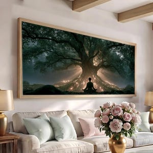 May include: A rectangular wall art print in a light wood frame depicting a silhouette of a person sitting in a meditative pose before a large, ancient tree. The tree base glows with warm light, contrasting against the dark, dense forest background.