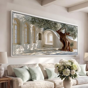 Può includere: Una stampa murale panoramica raffigurante un cortile mediterraneo con muri in pietra bianca, finestre ad arco e un ulivo nodoso. La scena mostra uno spazio esterno soleggiato con un pavimento in pietra e un arco architettonico.