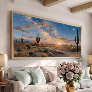 以下が含まれることがあります： 明るい木製のフレームに入った長方形の風景画のウォールアート。夕暮れ時の砂漠の風景が描かれています。背の高いサワロサボテン、岩の多い地形、まばらな砂漠の植生が、輝く地平線と星空の下に広がっています。