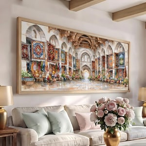 May include: A rectangular framed wall art print depicting a wide-angle perspective of a stone bazaar interior. The scene features multiple arched alcoves displaying colorful hanging rugs, textiles, and various ceramic pottery items on the floor.