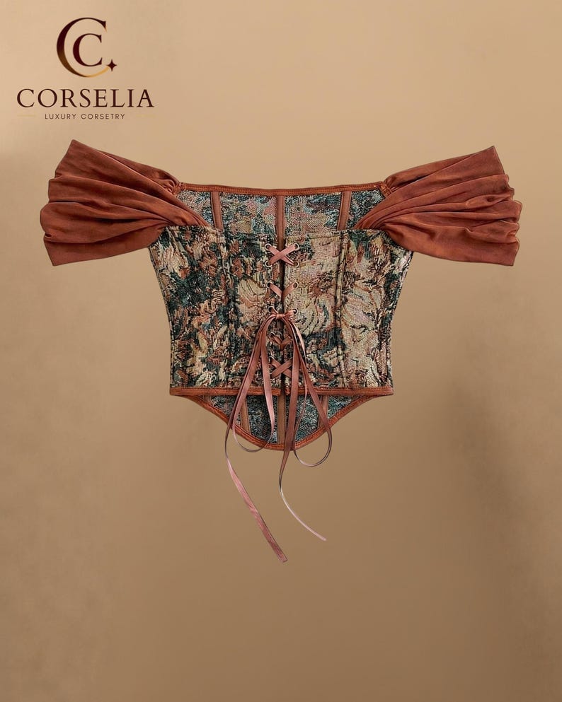 May include: A corset top featuring a multi-colored floral tapestry pattern with a front lace-up closure using thin ribbons. The garment includes off-the-shoulder sleeves made of solid rust-colored fabric and a pointed hemline at the bottom.