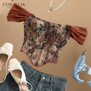 May include: A floral tapestry corset top with brown off-the-shoulder sleeves, a double-strand pearl necklace, white bow-accented flats, blue denim jeans, and a light blue handbag. The Corselia logo is visible in the upper left corner.