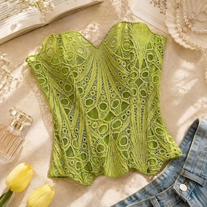 Può includere: Un top a corsetto senza spalline color verde lime caratterizzato da un intricato pizzo sovrapposto simmetrico con motivi geometrici e floreali. Il capo presenta uno scollo a cuore, cuciture verticali strutturate e un orlo smerlato, che mette in risalto un vivace e dettagliato ricamo su un tessuto di base a tinta unita.