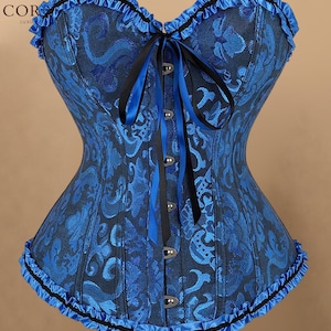 May include: A blue and black corset featuring a damask pattern, a sweetheart neckline with ruffled trim, and a front busk closure with metal clasps. The garment includes a black and blue ribbon lace-up detail at the center and ruffled hem.