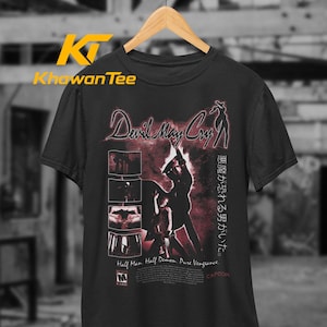 Puede incluir: Una camiseta negra de manga corta con un estampado gráfico del logotipo de Devil May Cry, la silueta de un personaje y cuatro paneles pequeños. El texto dice Half Man. Half Demon. Pure Vengeance. junto a caracteres japoneses y Capcom.