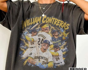 May include: A charcoal gray short-sleeve t-shirt featuring a graphic print of baseball player William Contreras in various poses. The design includes yellow text reading William Contreras and Brewers, with images of the player in a uniform.
