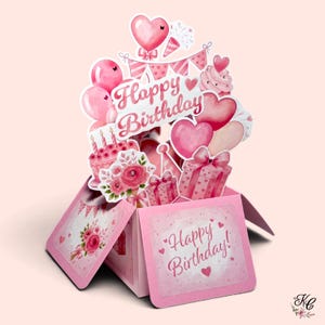May include: A pink pop-up greeting card featuring the text Happy Birthday. The design includes watercolour illustrations of pink balloons, hearts, a birthday cake with candles, gift boxes, party banners, and flowers in various shades of pink.