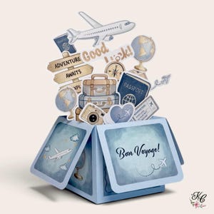 May include: A light blue pop-up greeting card featuring travel-themed cutouts including an aeroplane, a globe, a compass, stacked suitcases, a camera, and passports. The card displays the text Good Luck and Bon Voyage in dark blue script.