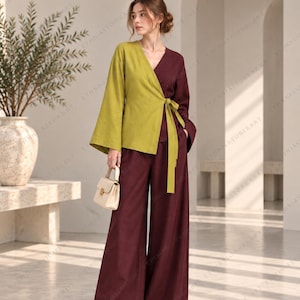 May include: A two-tone wrap top featuring a lime green left side and a deep burgundy right side with long flared sleeves and a matching tie closure, paired with high-waisted wide-leg trousers in matching burgundy and a small cream handbag.