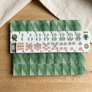 A collection of green and white tiles arranged on a wooden surface, with some tiles featuring images of animals and numbers.