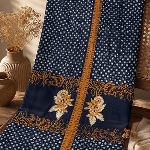 Op de afbeelding: Een rechthoekig stuk stof met een donkerblauwe achtergrond en een wit sterrenpatroon, geaccentueerd door een centrale verticale gouden Griekse rand en horizontale banden met oranje bloemlijnen en witte paisley-motieven.