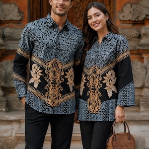 May include: Two long-sleeved button-down shirts featuring a black and blue geometric batik pattern on the upper section and sleeves, contrasted with a central vertical panel of intricate gold floral embroidery on a solid black background.