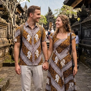 Könnte beinhalten: Ein kurzärmeliges Hemd mit Knopfleiste und ein knielanges Kleid, beide mit braun-weißem Batikmuster, diagonalen Streifen und Blumenmotiven. Das Hemd wird mit einer hellen Hose kombiniert, während das Kleid einen eckigen Ausschnitt hat.