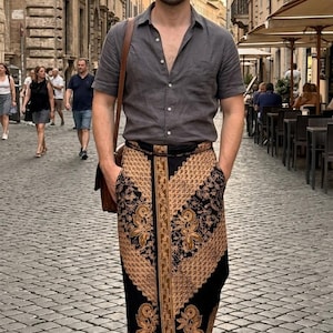 Può includere: Una camicia a maniche corte grigio antracite abbottonata abbinata a una gonna lunga a portafoglio con motivo batik nero e marrone chiaro con disegni floreali, indossata con mocassini in pelle marrone e una borsa a tracolla in pelle marrone.