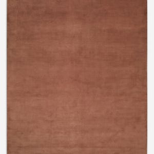 May include: A rectangular area rug featuring a solid, uniform terracotta brown color. The surface has a dense, short-pile texture with subtle variations in shading across the flat, even weave, creating a consistent and monochromatic appearance.
