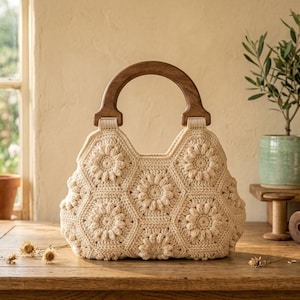 May include: A cream-colored crochet handbag featuring a floral hexagon pattern and a dark brown wooden semi-circular handle. The bag is constructed from interconnected yarn motifs, creating a textured surface with a central flower design.