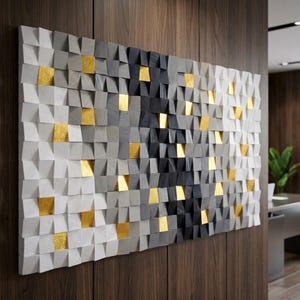 May include: A rectangular wall art piece composed of numerous small, square wooden blocks arranged in a grid. The blocks feature a gradient of colors ranging from white and light gray to dark charcoal and black, accented by scattered gold leaf squares.