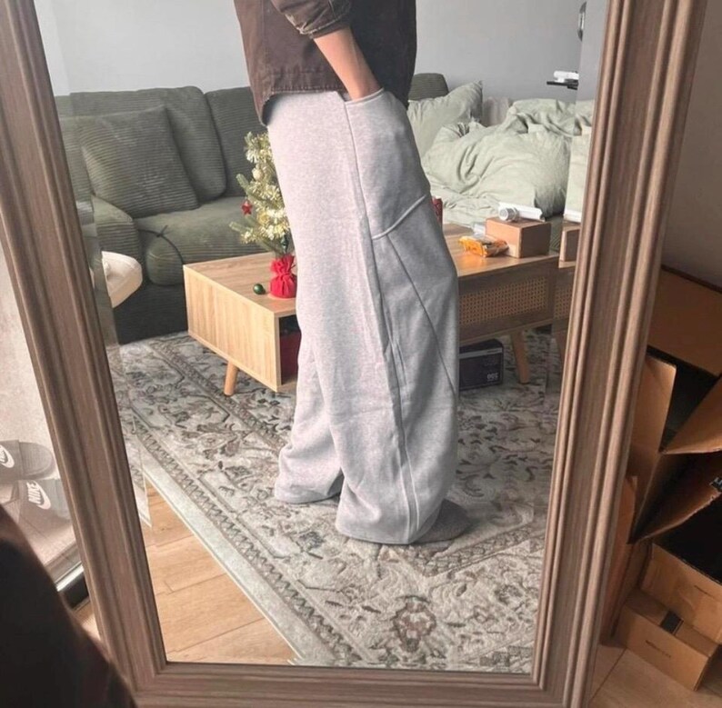 Peut inclure: Pantalon de jogging gris clair &agrave; coupe large, taille haute, avec des coutures verticales marqu&eacute;es sur le devant de chaque jambe. Ce pantalon est dot&eacute; de poches lat&eacute;rales profondes et est confectionn&eacute; dans un tissu chin&eacute; doux et confortable.