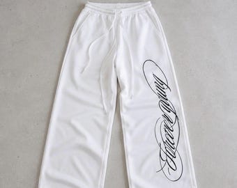 Pantalones deportivos con estampado de escritura, joggers blancos de pierna ancha con gráfico caligráfico en la pierna, pantalones de descanso relajados, estilo urbano Y2K, unisex.