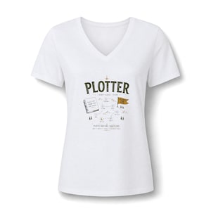 May include: A white V-neck t-shirt featuring a graphic design with the text PLOTTER, DON'T GUESS / PLAN, and PLOTS BEFORE PANTSING. The illustration includes a spiral notebook, a mountain path map with numbered steps, and a small brown flag.