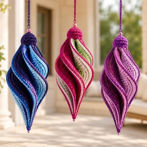 May include: Three hanging crochet ornaments with a spiral, teardrop shape. The left ornament features shades of blue and purple. The center ornament displays pink, green, and white. The right ornament shows shades of purple and light pink.