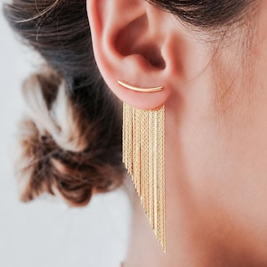 May include: A gold-toned ear crawler earring featuring a curved bar that sits along the earlobe, with a cascading fringe of multiple thin, delicate gold chains hanging downwards in an asymmetrical, graduated length. The text In September is visible.