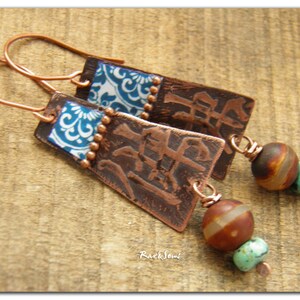 May include: Copper earrings with blue and white patterned squares, brown and turquoise beads, and the Chinese character for "peace" embossed on the copper.