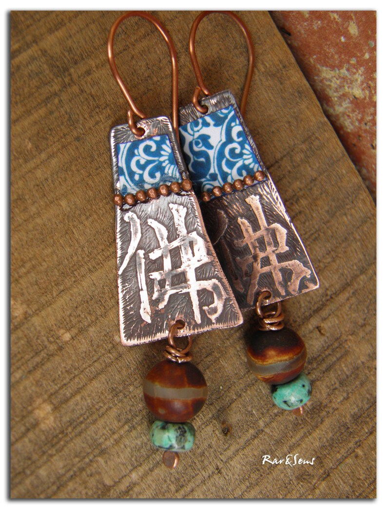 May include: Copper earrings with blue and white patterned metal accents, brown and turquoise beads, and the Chinese character for "peace" embossed on the metal.