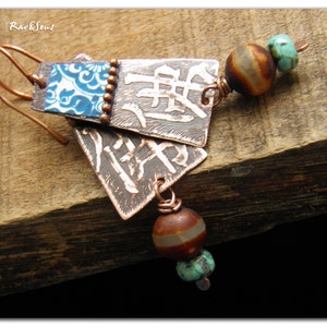 May include: Copper earrings with blue and white patterned tiles, brown and white agate beads, and turquoise beads. The earrings are hanging from a wooden surface.