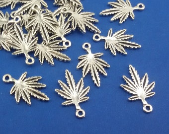 May include: A pile of silver-toned metal cannabis leaf charms with a loop for attaching to jewelry or other crafts.
