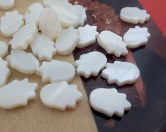 May include: A collection of white, mother-of-pearl, hand-shaped, decorative tiles.
