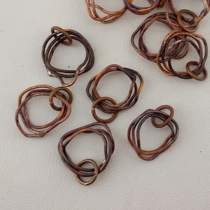 Peut inclure: Huit anneaux en fil de cuivre, chacun avec une forme et un design uniques. Les anneaux sont de tailles différentes et ont un aspect rustique et vieilli.