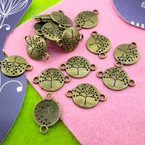 May include: A collection of 12 bronze-coloured metal charms featuring a tree design. Each charm has two loops for attaching to jewellery or other crafts.