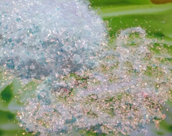 Könnte beinhalten: Ein Haufen schimmernder Glitzer in Blau- und Weißtönen. Der Glitzer befindet sich auf einer grün-weißen Oberfläche.