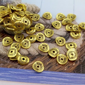 Puede incluir: Una colección de adornos metálicos de color dorado con un diseño floral. Los adornos están dispersos sobre una superficie texturizada.