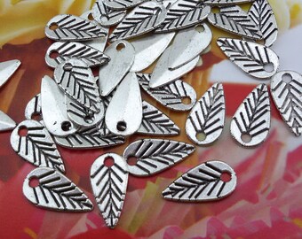 May include: A collection of silver-toned metal charms shaped like leaves. The charms have a detailed design and are perfect for jewelry making or crafting projects.