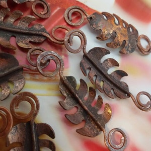 May include: A collection of copper leaf charms with intricate details and a rustic finish. Each charm features a leaf shape with a wire loop for attaching to jewelry or other crafts.
