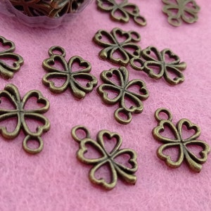 May include: A collection of bronze-coloured four-leaf clover charms with a loop at the top for attaching to jewellery or other crafts.