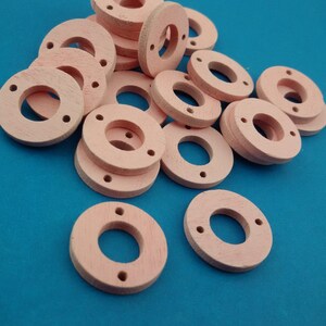 May include: A pile of pink wooden rings with a hole in the centre. The rings are stacked on top of each other and are arranged in a random pattern.