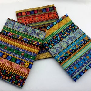 Op de afbeelding: Drie stofstalen met kleurrijke geometrische patronen en gouden accenten. De patronen omvatten strepen, spiralen en vierkanten.