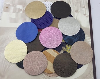 May include: Assortment of round leather pieces in various colors and textures, including gold, pink, blue, brown, and gray. The leather pieces are arranged in a circular pattern on a white surface.