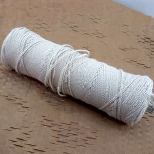 May include: A roll of natural white cotton twine, perfect for crafting, wrapping, or decorating. The twine is wound tightly and has a natural, rustic look.