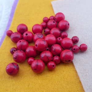 May include: A pile of red and white marbled beads. The beads are round and have a smooth, polished finish.
