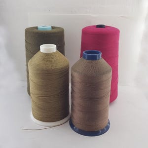 Può includere: Quattro bobine di filo, due sono marroni, una è verde oliva e una è rosa.