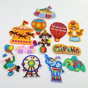 Könnte beinhalten: Eine Sammlung von zwölf bestickten Stoffaufnähern mit Zirkusmotiven, darunter ein Karussell, Heißluftballons, ein Affe auf einem Ball, ein Tiger, ein Clown mit Luftballons, ein Riesenrad, ein Elefant und ein Schild mit der Aufschrift Circus.