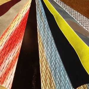 May include: A collection of 12 different leather samples, each with a unique texture and colour. The samples are arranged in a fan shape, with the darkest colour at the bottom and the lightest colour at the top.