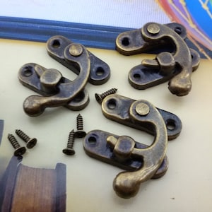 Puede incluir: Cuatro cierres de pestillo de latón antiguo con una manija de palanca y cuatro tornillos. Los cierres están diseñados para usarse en cajas, cofres u otros artículos de madera.