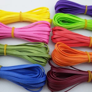 May include: Assortment of colourful plastic cords, including purple, green, pink, red, orange, green, blue, and burgundy.