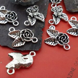 May include: Silver tone metal rose flower charms with two jump rings. The charms feature a rose with leaves and are perfect for jewelry making.