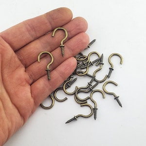 Peut inclure: Une collection de petits crochets à vis en métal de couleur laiton antique, chacun doté d'une partie supérieure incurvée et d'une base filetée. Ces fixations matérielles sont conçues pour être vissées, avec une finition métallique.